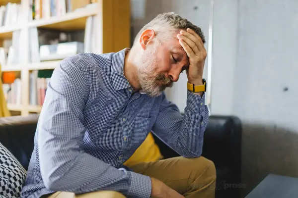 Poor blood circulation - A man over 40, sitting down, looking tired, with cold hands.